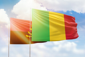 Sunny blue sky and flags of mali and angola
