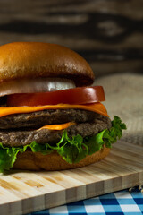 vertical shot of salad cheeseburger with lettuce,tomato and onion, on woode surface. copy space, text area