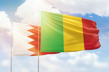 Sunny blue sky and flags of mali and bahrain