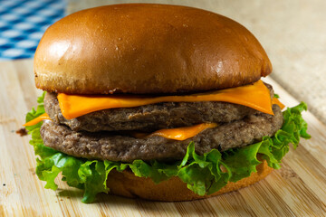 top view shot of two meat cheeseburger with lettuce, on wooden surface.