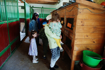 Children on an animal farm look at cages with rabbits.