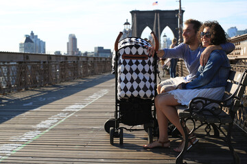 Young family with a baby stroller walks along the Brooklyn Bridge in New York USA