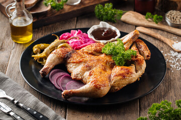 Portion of chicken tobacco dish with sauce and salad on wooden background