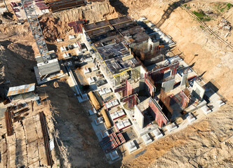Сonstruction site with foundation for monolithic reinforced building. Monolithic slab foundation and concrete pouring. First floor slab rebar installation. Tower crane on formwork at construction..