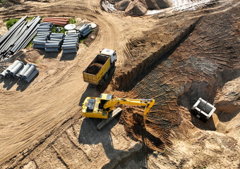 Excavator load sand in dump truck. Earthworks on construction site. Dig ground for sewer construction and sanitary sewer. Sewage drainage and concrete pipes. Laying sewer pipe and storm sewer.