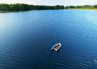Fishermen boat on lake. Fishing for river fish from a motor boat using a fishing rod or spinning rod. Sports fishing on water. Rest in wild. Fishing boat with a fisherman on lake while catching fish.