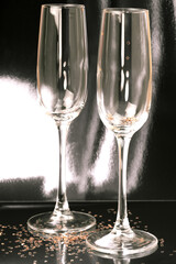 Festive dark black mysterious background with glassware. Two empty shiny glasses for wine and champagne on the table