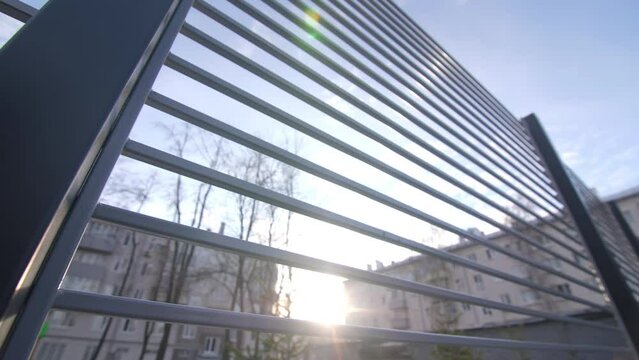 New metal fence made of thin beams in empty yard of apartment building in winter evening extreme close view