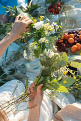 Unrecognized woman weaves a wreath of wild flowers for the summer solstice.