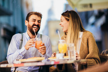 Young couple sitting in a restaurant eating pizza outdoor.