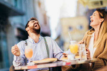 Young couple sitting in a restaurant eating pizza outdoor.