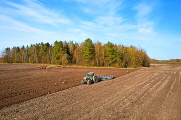 Tractor plowing field. Tractor plow soil cultivating. Cultivated land and soil tillage. Agricultural tractor on farm field cultivation. Tractor disk harrow plowing farm field. Agronomy and agrarian..