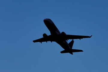 A large modern plane flies in the sky, a view from below from the ground to the belly of the aircraft.