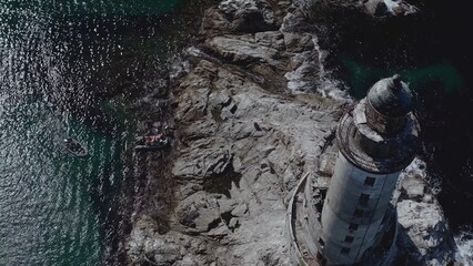 Lone lighthouse located near to ocean coast with rocks water shot by drone aerial view background...
