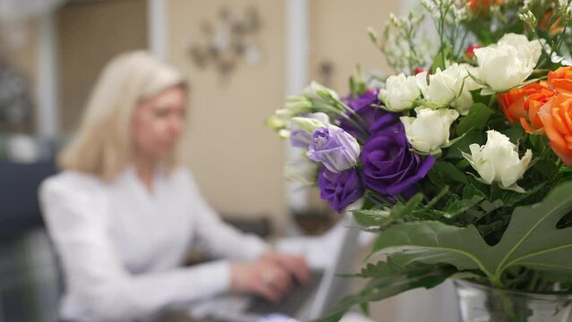 Frau arbeitet zu Hause mit sch&ouml;nem Blumenstrauss