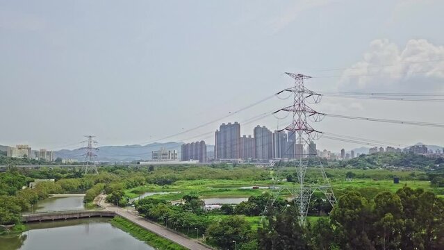 A dynamic aerial shot of high-voltage electric towers along the town of Yuen Long in Hong Kong. These are double-circuit type of towers and they are used for voltages ranging from 110 to 315 kV.