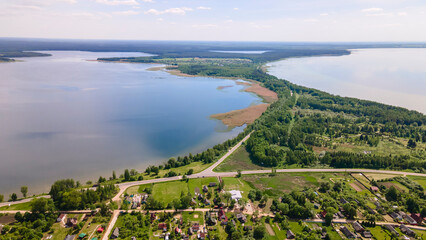 Aerial view of lake and small village. Village near the lake. Aerial view of the village and trees on the shore of lake.