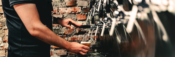 bartender hand at beer tap pouring a draught beer in glass serving in a bar or pub. tap room