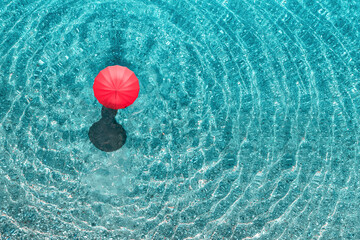 Top view of woman with red summer umbrella walking in tropical blue, turquoise transparent water...