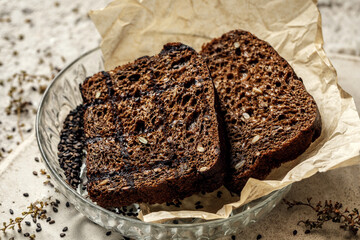 Organic wholegrain rye healthy bread with seeds in glass plate on baking paper. Healthy lifestyle concept
