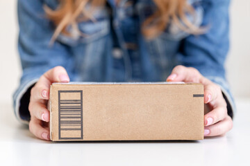 Woman holding in hands delivered goods in cardboard box. Mock-up friendly design with copy space.