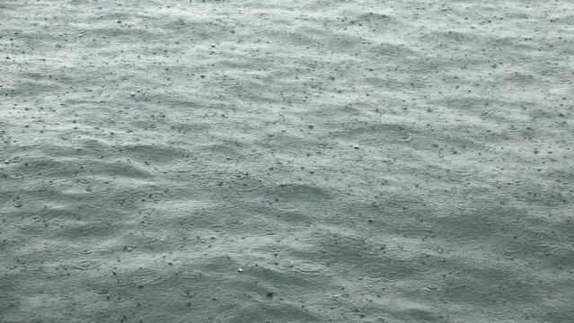 Slow-motion heavy rain in calm ocean waves in Hong Kong. Sad melancholy.