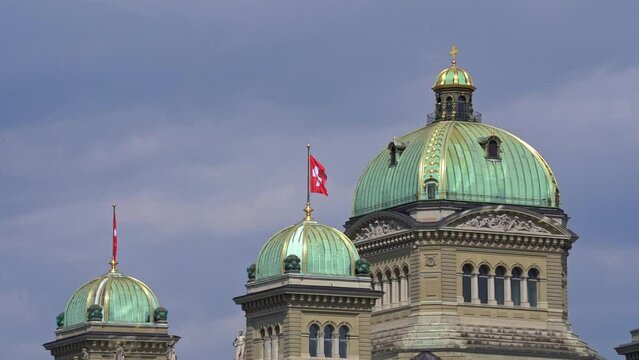 Swiss flag waving at Federal Palace of Switzerland (German Bundeshaus), residence of national Swiss government and parliament. Slow motion movie shot June 16th, 2022, Bern, Switzerland.