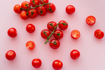 Top view of organic cherry tomatoes on branches on pink background.