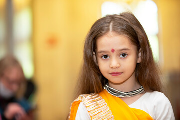 Beautiful little Indian girl in sari looks at the camera and smiles.