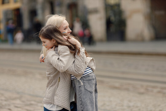 Girl hugging her nother with a flag of Ukraine on a cheek