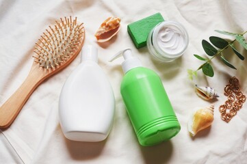 Flat lay still life beauty photography. Wooden comb, white shampoo bottle, green liquid soap...