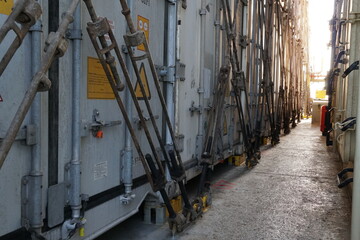 Fototapeta premium Row of the containers from different shippers secured on main deck of the ship and lashes with lashing bars, turnbuckles and bottom and automatic twist locks. 