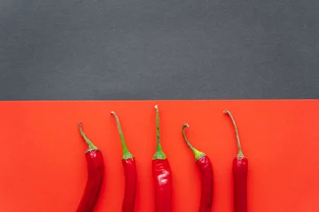 Fotobehang Top view of chili peppers on red and black background. © LIGHTFIELD STUDIOS