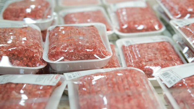 Close up of hands of woman choosing chopped meat at a grocery store, vacuum packing food. Shopping, sale and lifestyle concept