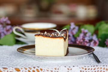 A piece of cake and a cup with a drink on the table.