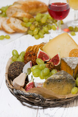 fresh fruit, wine and cheese in a basket, vertical