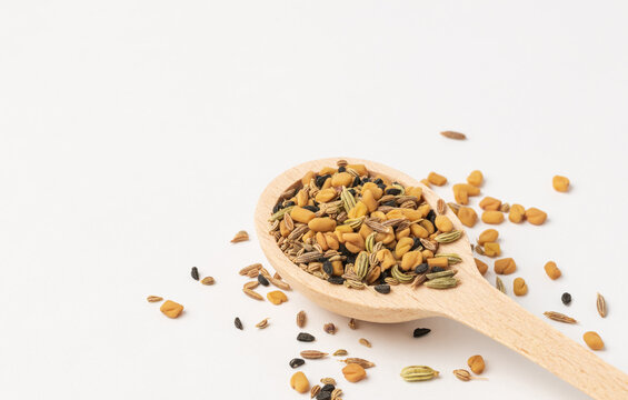 Wooden spoon with Panch phoron  or panchpuran  Indian  five spice seeds  mix  consisting of fenugreek, fennel, cumin, mustard seeds, onion seeds or black cumin in  on white