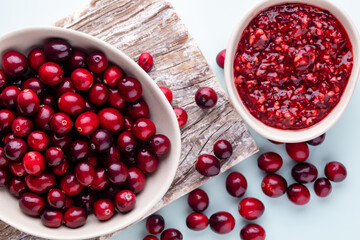 Cranberries in white bowl on pastel background.