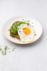 Keto breakfast fried egg, avocado and bread in a white plate. Keto diet concept.