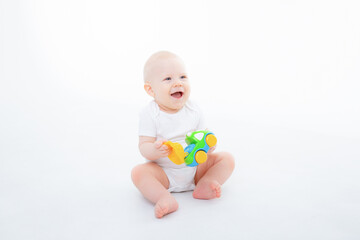 Fototapeta na wymiar baby boy in a white bodysuit is sitting playing with toy cars on white background