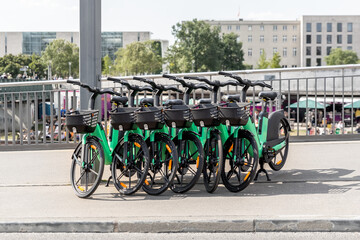Many modern green electric e bikes sharing parked on city street. Self-service street transport...