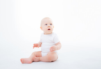 baby boy in white bodysuit sitting on a white background