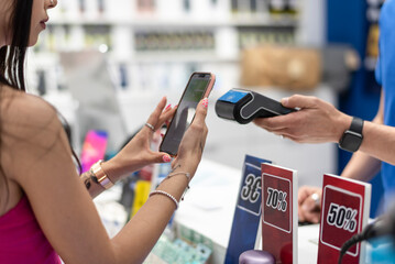 Beautiful woman pays with her mobile phone in dataphone a cover bought in a mobile store