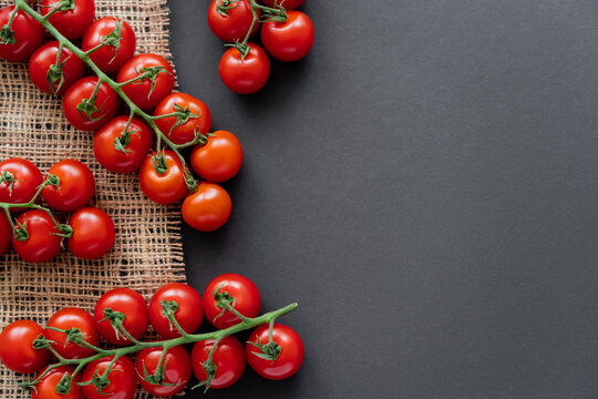 Top view of fresh cherry tomatoes on sackcloth on black background.