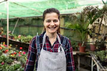 Happy smiling woman working in flower garden shop