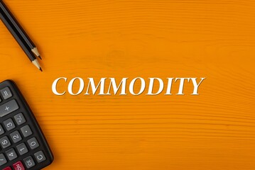 COMMODITY - word (text) on a yellow wooden background, a calculator and a pencil. Business concept...
