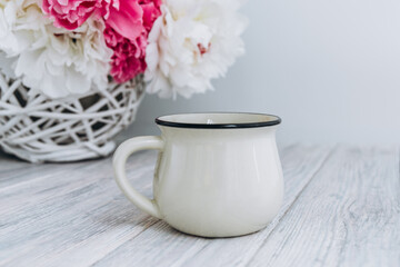 Mock up of white blank coffee mug perfect for your own design or quote with peony flowers on background.