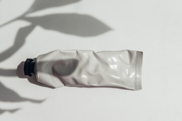 Crumpled cream tube with leaves shadows, mockup zero waste concept. 