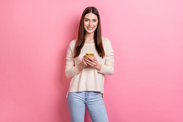 Portrait of attractive cheerful brown-haired girl using device gadget isolated over pink pastel color background