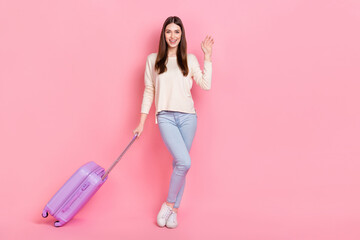 Full length body size view of attractive cheerful girl holding bag departure waving hi isolated over pink pastel color background